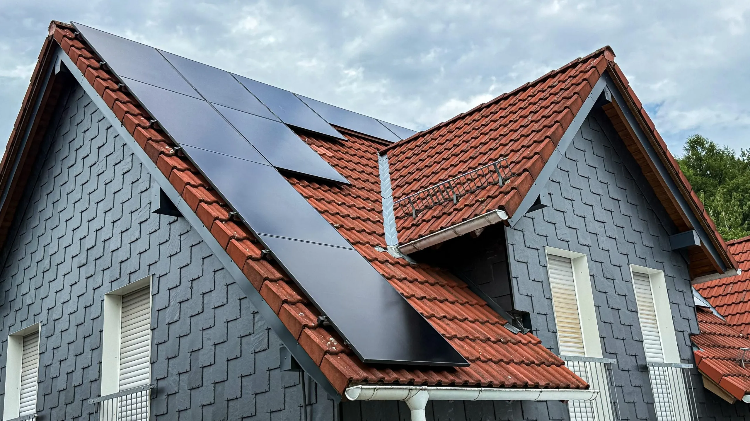 Photovoltaikanlage mit schwarzen Modulen auf dem Ziegeldach eines Wohnhauses